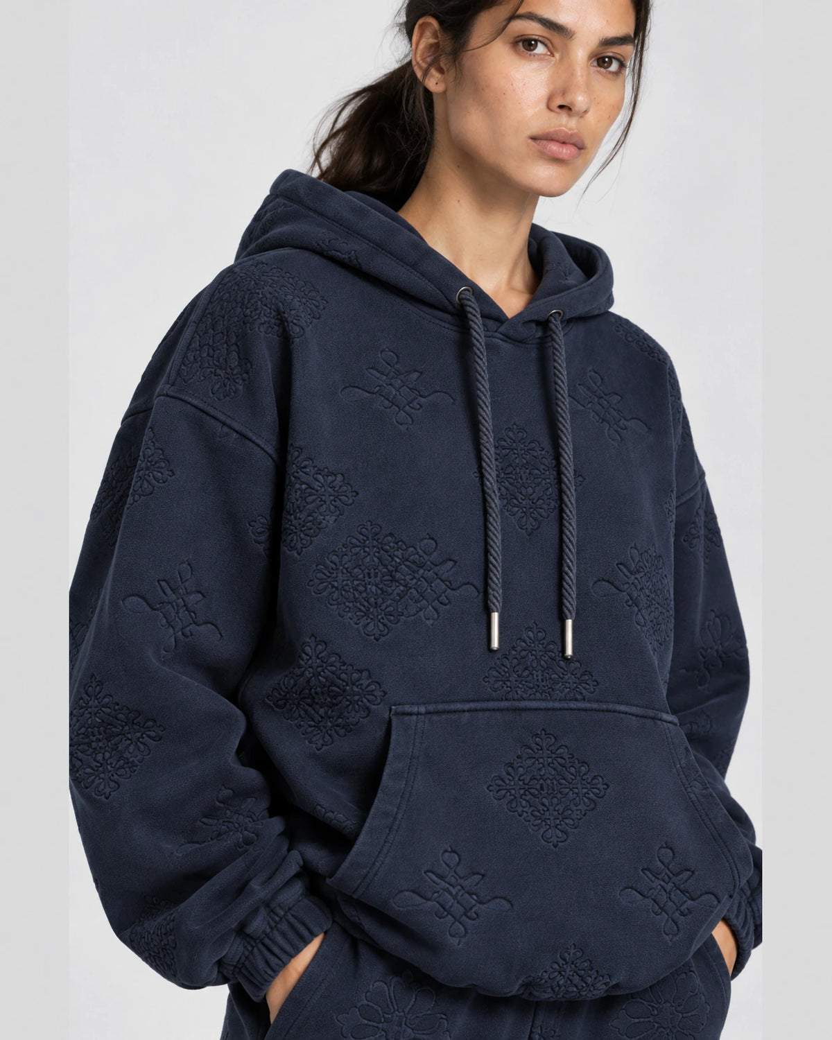 MOMANI Emblem Jacquard Hoodie in Navy, worn by a model, close detail