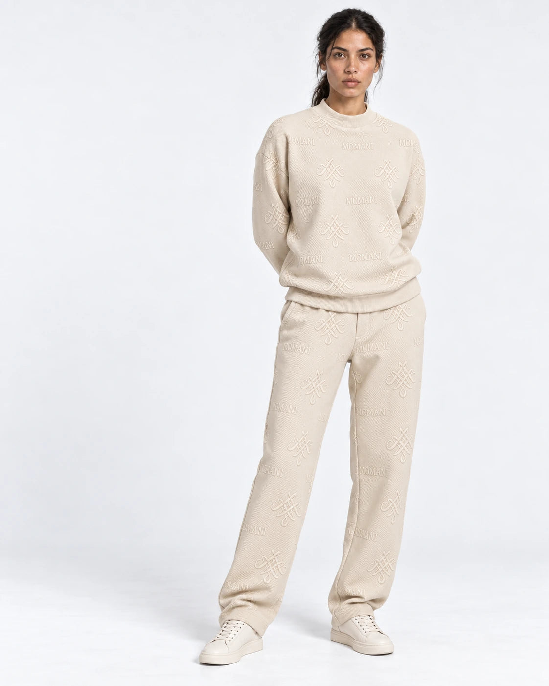 A model in the MOMANI Emblem sweatshirt and trousers in the white studio